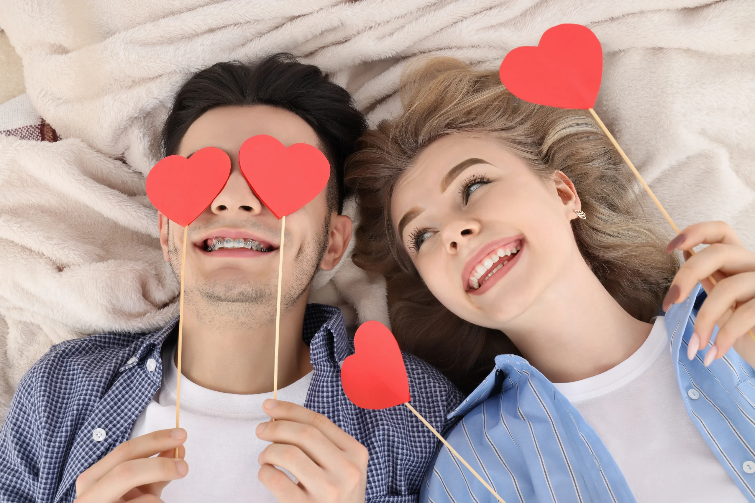 Couple holding red hearts over eyes, prioritizing sexual health with HerMister.