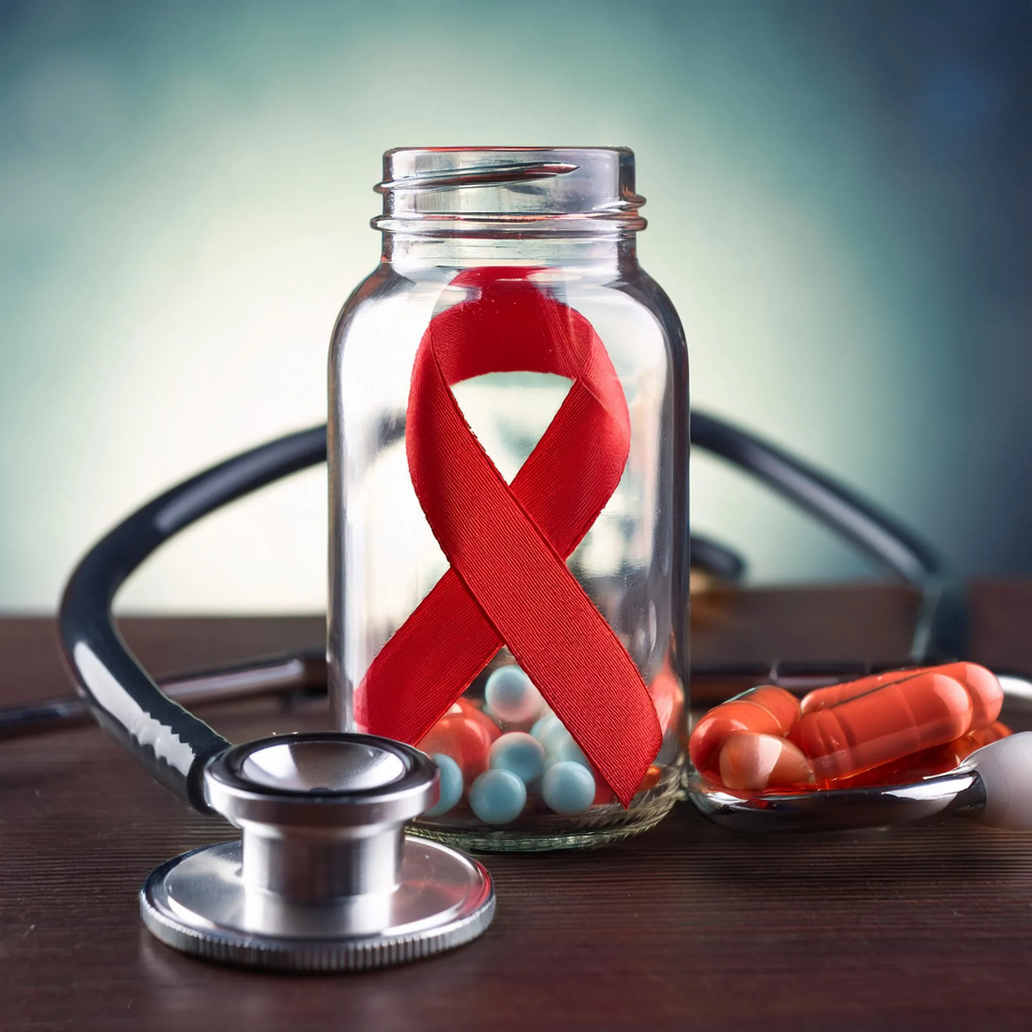 Red ribbon with pills and stethoscope representing HIV PrEP medications, prep effectiveness HIV awareness, and prep medication support.
