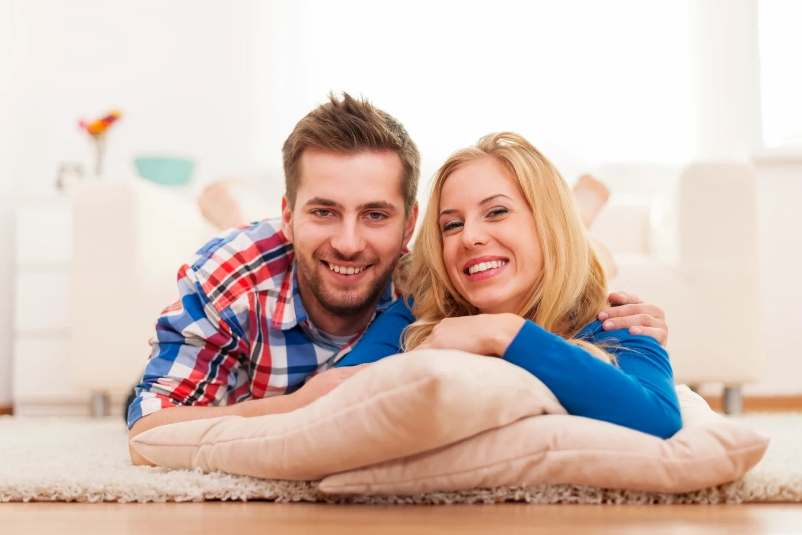 A happy young couple relaxing at home, illustrating the ease of using an at home STI testing kit.