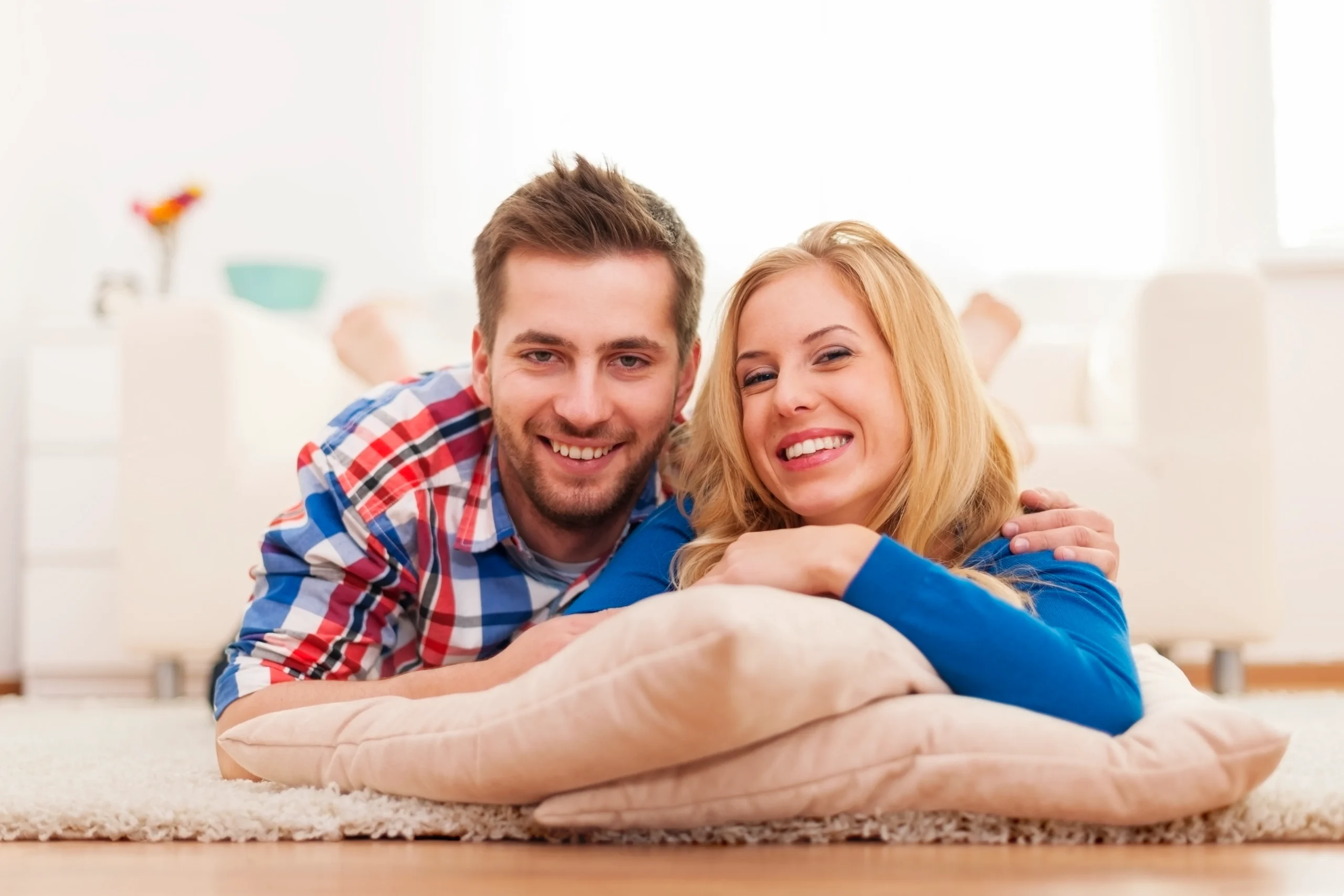A happy young couple relaxing at home, illustrating the ease of using an at home STI testing kit.