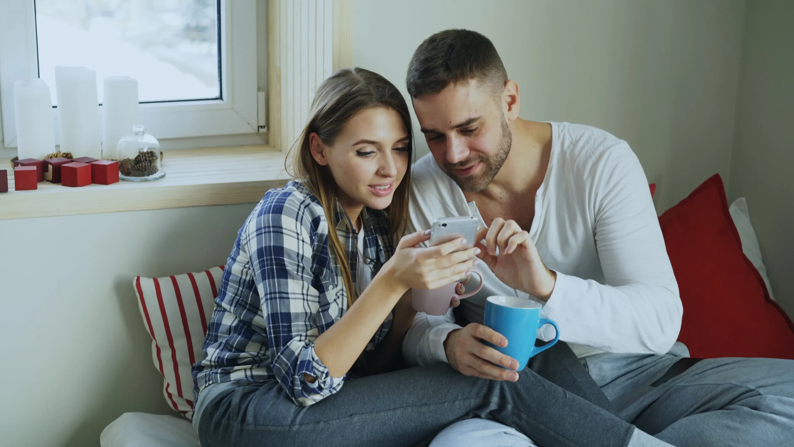 A couple sitting together in bed while checking a smartphone to research Nurx alternatives for PrEP and select the best online PrEP provider.