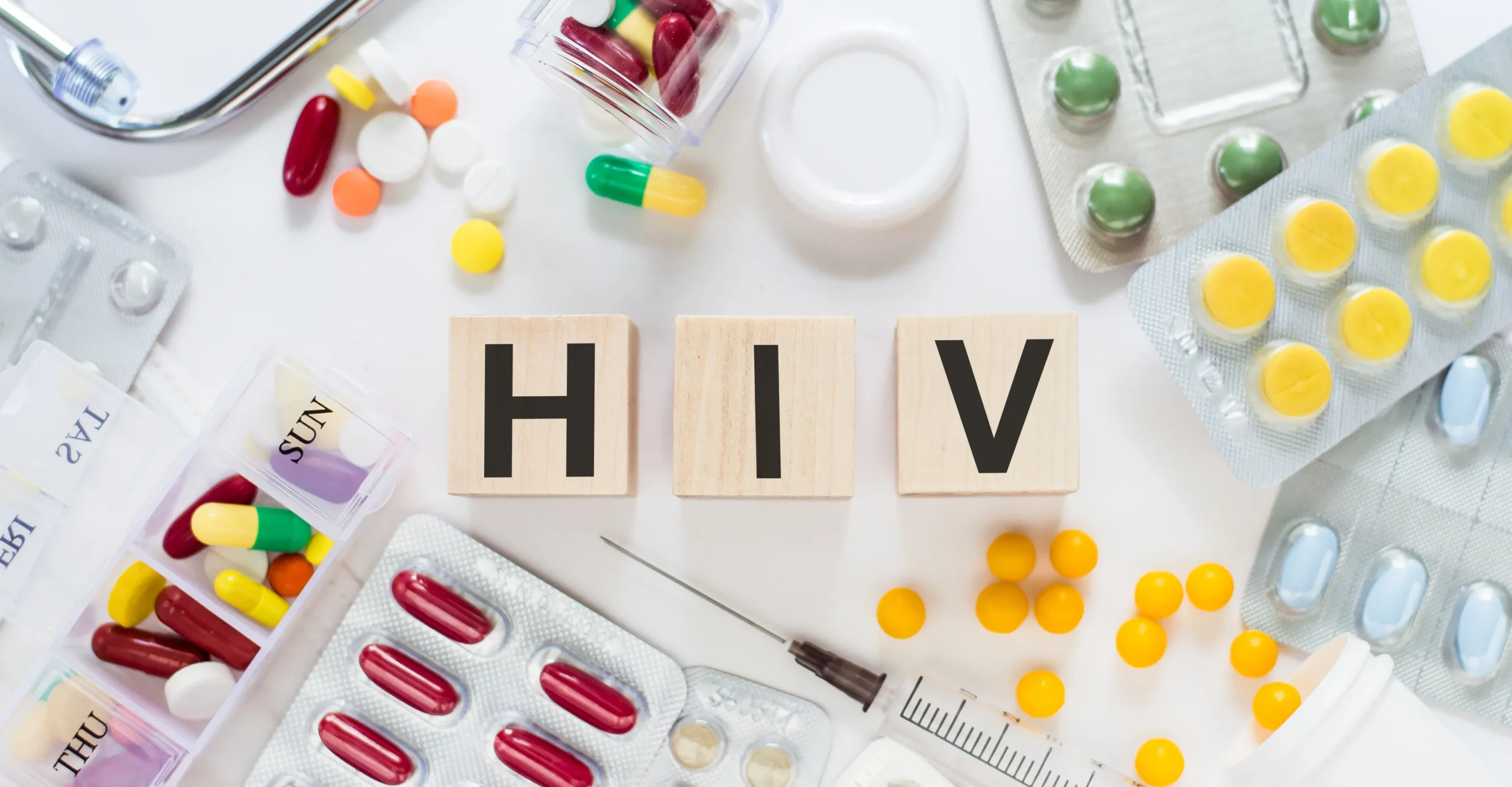 Wooden blocks spelling HIV surrounded by medical capsules and tablets, representing online STD treatment prescription options.