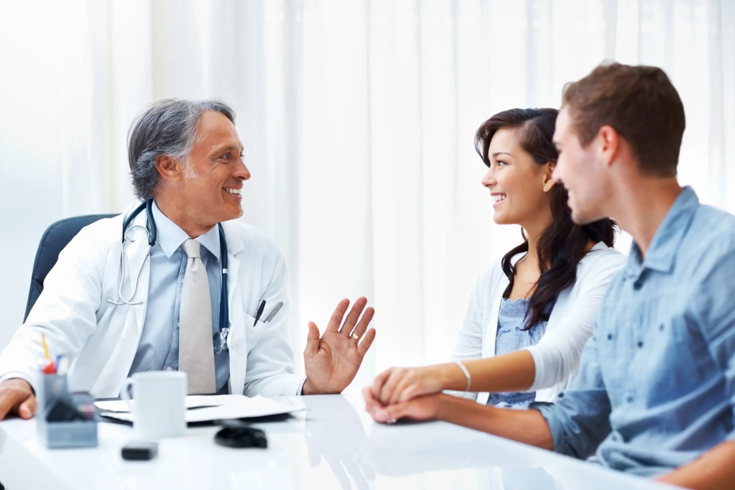 A smiling doctor talking to a young couple during a virtual or in-person consultation about getting PrEP online Florida through PrEP telehealth.
