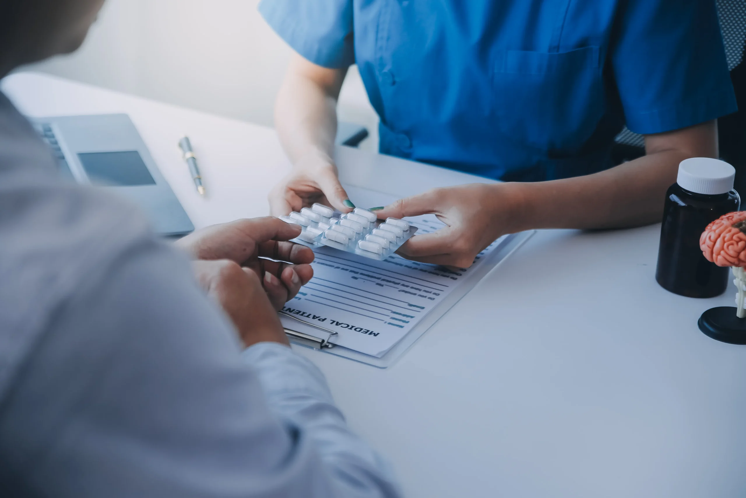 A healthcare professional hands a blister pack of pills to a patient during a consultation regarding PrEP therapy and Aids prevention medication.