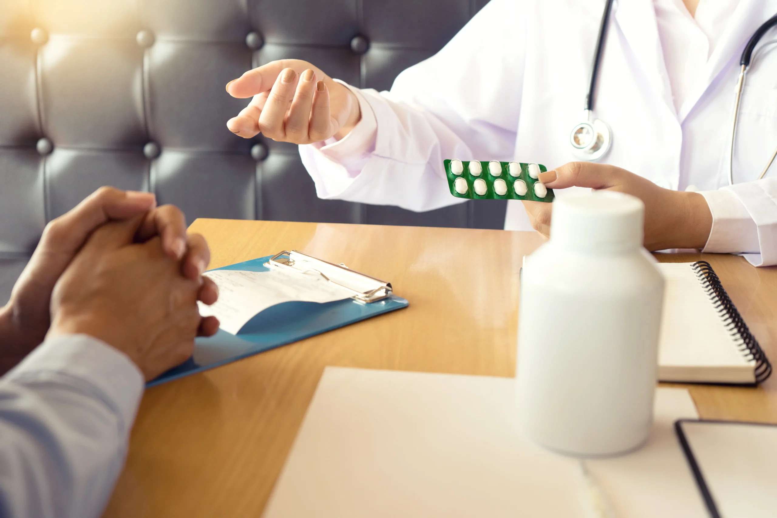 MA doctor handing medication over a desk to a patient, illustrating how to get an online PrEP prescription and get PrEP online through telePrEP Florida.