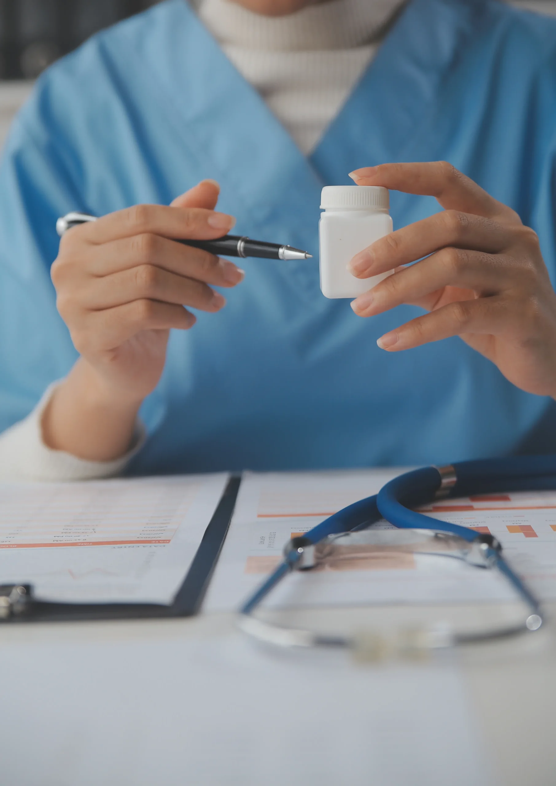 A medical provider pointing a pen at a prescription bottle over patient charts, discussing telehealth solutions like anonymous HIV testing online and private STD testing services.