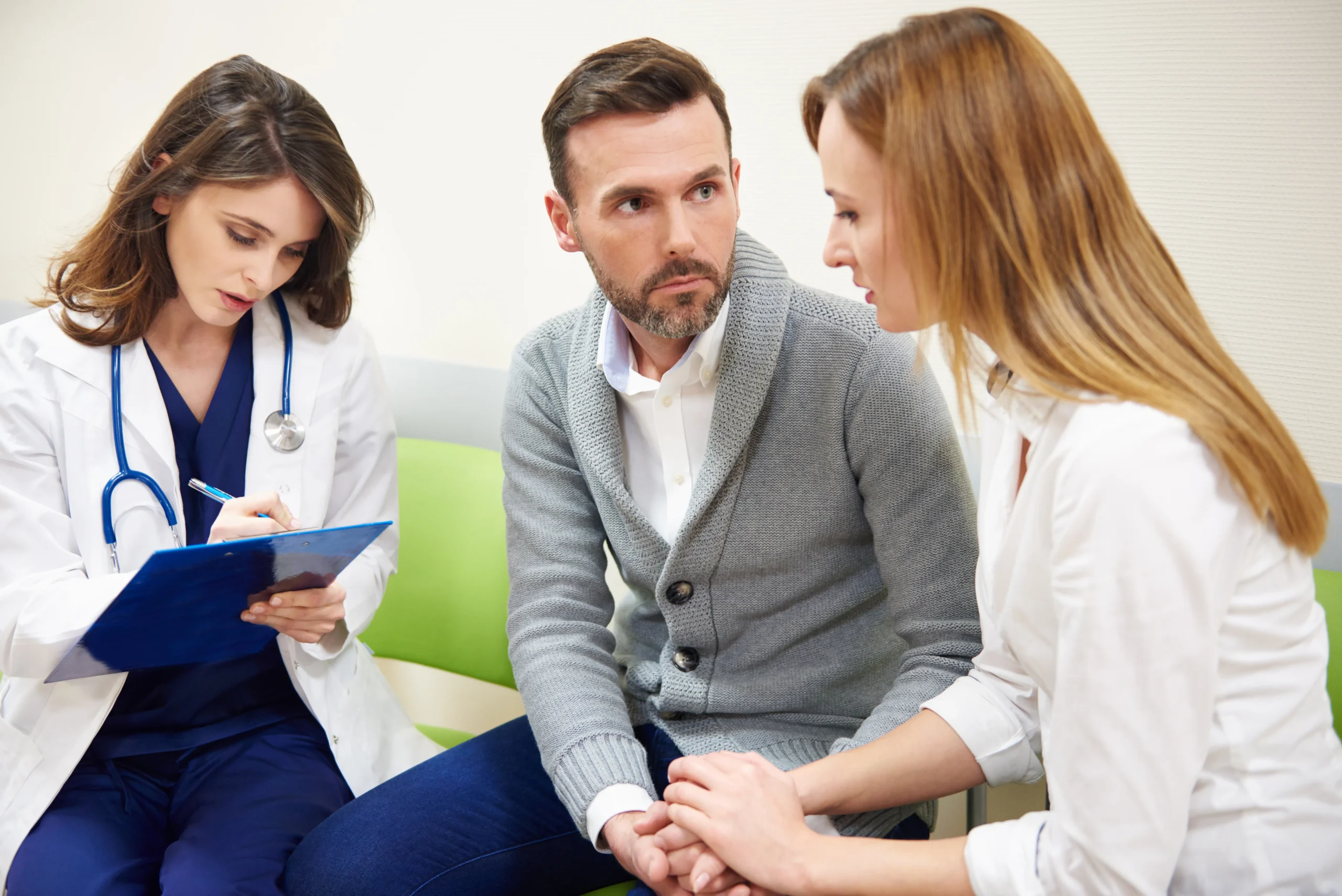 A physician taking clinical notes on a clipboard while debunking common PrEP myths with a couple during a consultation.