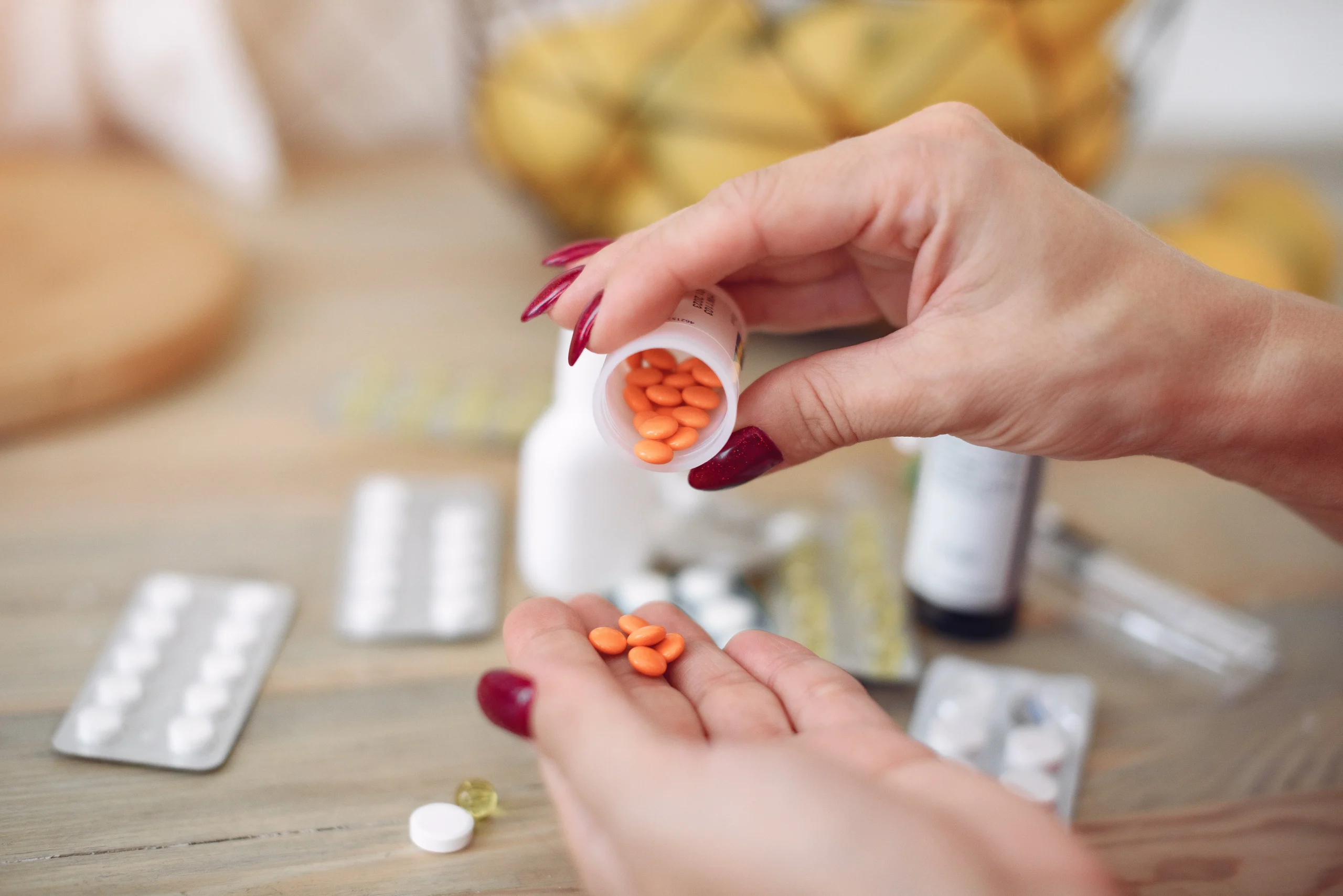 A person pouring small orange tablets into their hand to maintain a daily PrEP medication schedule.