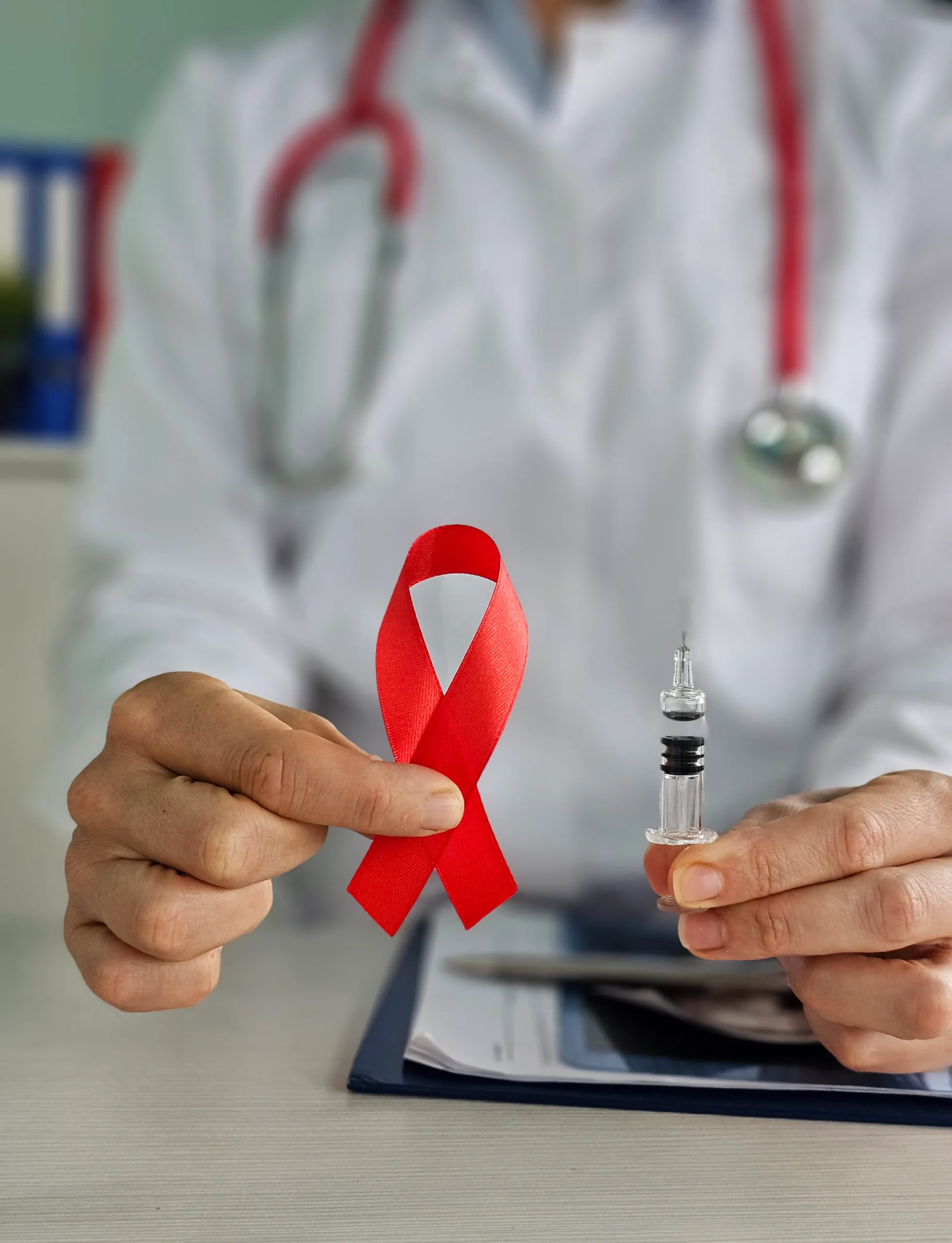 A healthcare provider holding a red awareness ribbon and syringe to advocate for HIV prevention.