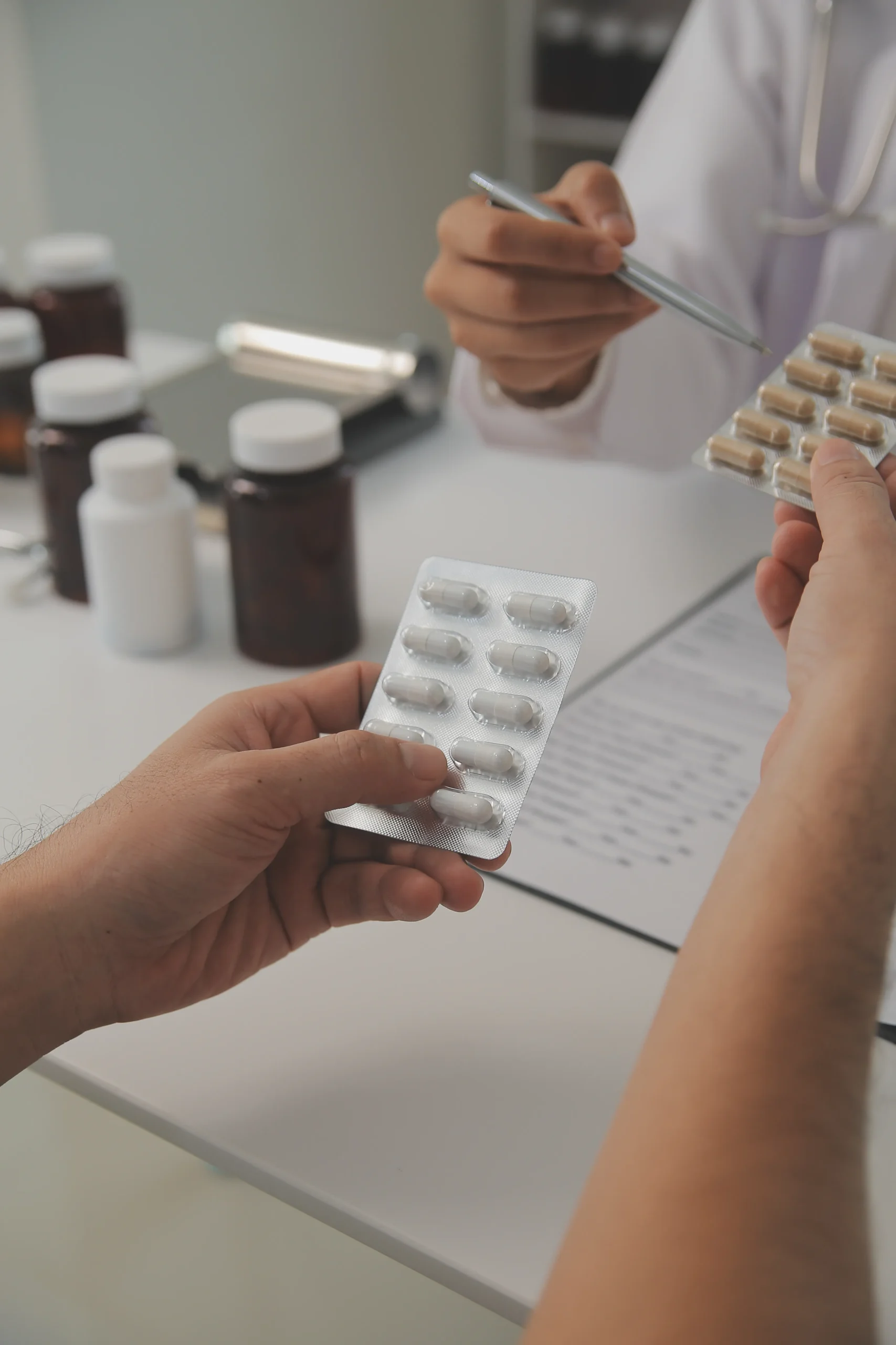 A doctor pointing with a pen to blister packs of PrEP medication being held by a patient.