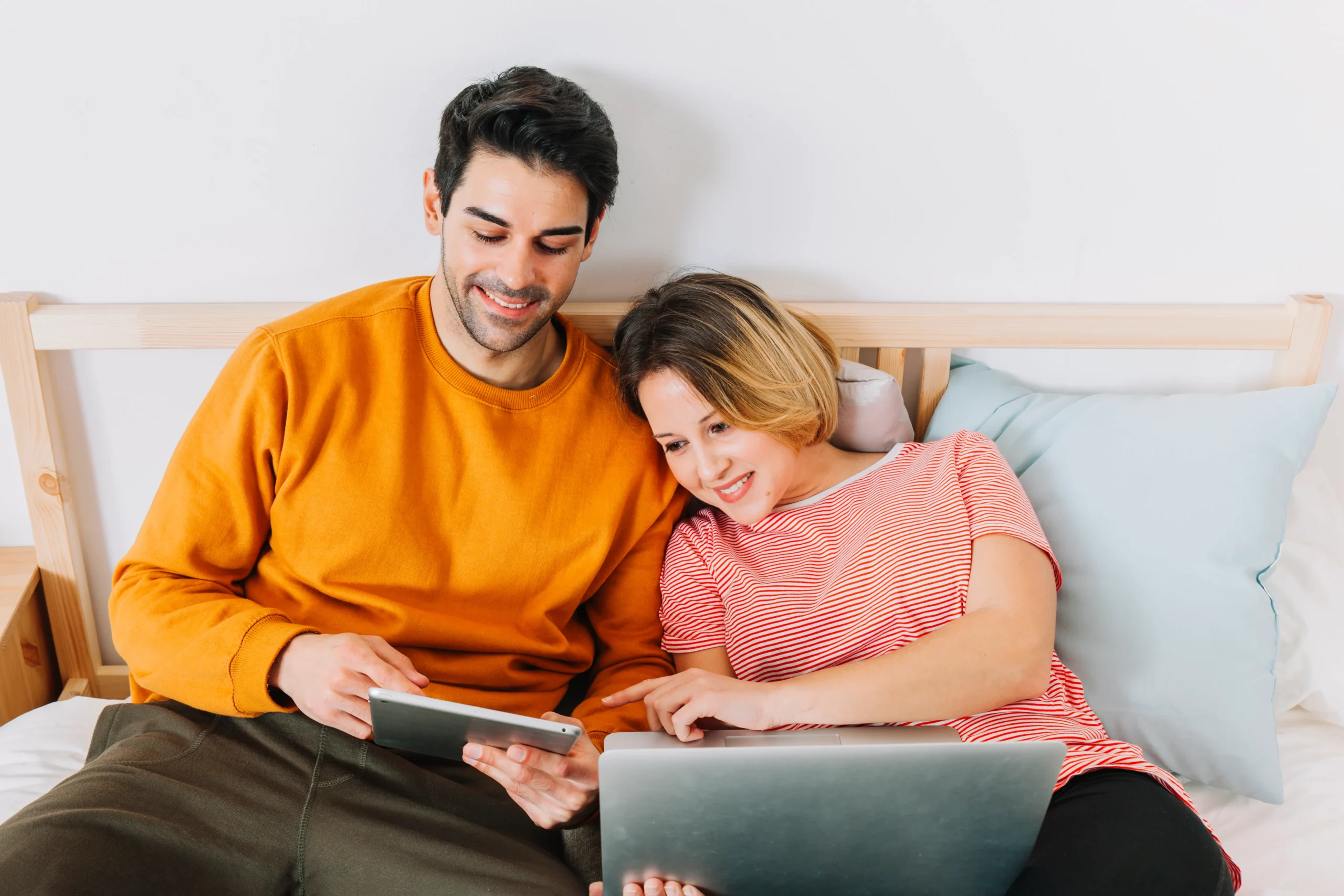 Couple relaxing on a bed while browsing digital healthcare services and ordering STI testing kits.