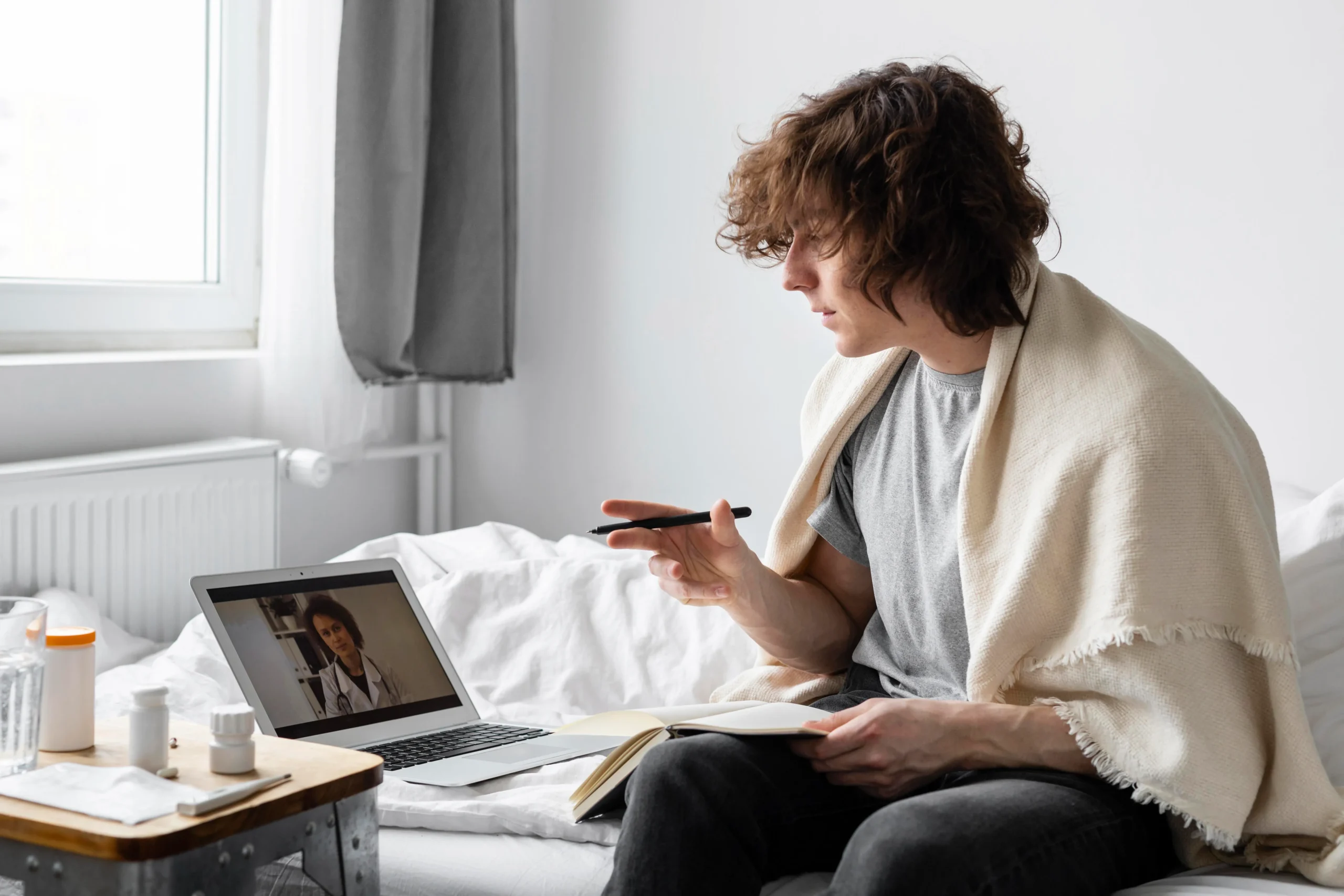 Individual sitting in bed having a video consultation with a telehealth PrEP provider.
