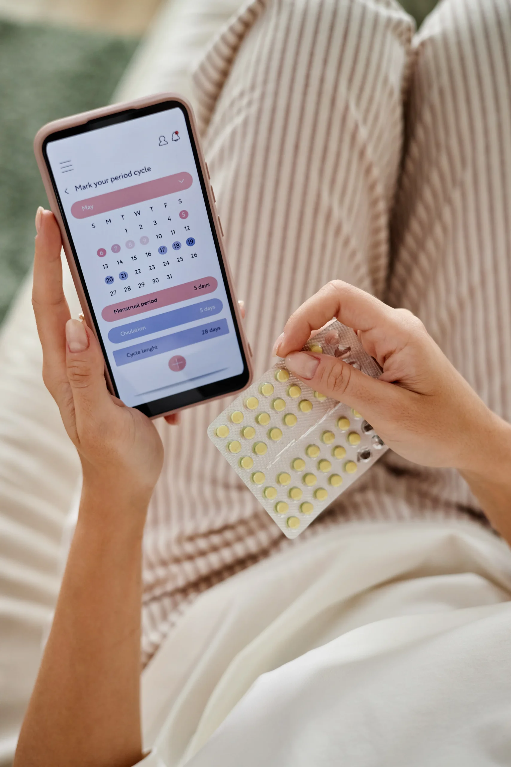 Person tracking daily medication schedules on a smartphone while holding a blister pack for PrEP home delivery.